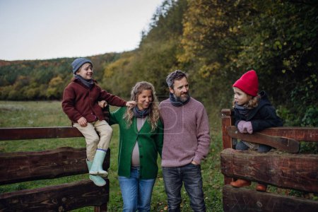 Photo for Portrait of family outdoors going on walk in nature. Mother, father and kids spending time outdoors during a cold autumn day. - Royalty Free Image