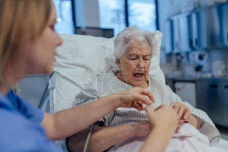 Infirmière prenant soin d'un patient âgé en soins intensifs, icu. Femme âgée après un accident vasculaire cérébral, crise cardiaque en convalescence, couchée dans un lit d'hôpital.