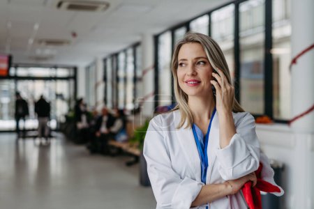 Photo for Portrait of beautiful female doctor with christmas hat in hand phone calling. Working in hospital on the Christmas day, Christmas Eve. Female doctor working a Christmas shift and cant be with her - Royalty Free Image