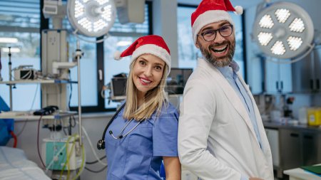 Téléchargez les photos : Équipe médicale d'urgence pendant Noël avec chapeau de Père Noël sur la tête. Équipe de médecins et d'infirmières qui travaillent un quart de Noël à l'hôpital, le personnel de l'hôpital ne peut pas être avec la famille pendant le jour de Noël et - en image libre de droit