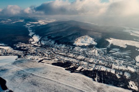 Photo for Aerial view of a small village surrounded by a forest during winter. Drone view of snowy landscape, concept of the winter christmas holidays. - Royalty Free Image