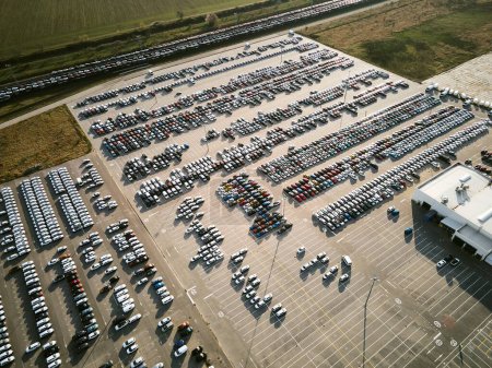 Téléchargez les photos : Vue aérienne d'un parc de stationnement massif dans une usine de fabrication de voitures avec des véhicules nouvellement produits garés en rangées. - en image libre de droit