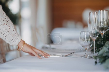 Foto de Mujer preparando, escenario de mesa romántica para la recepción de la boda interior, celebración. Decoración de mesa de boda de lujo, mesa de eventos especiales con arreglos de flores frescas. - Imagen libre de derechos