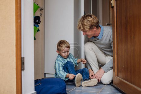 Photo for Boy getting ready for school, putting on the shoes, getting dressed. Father taking son to school before going to work. - Royalty Free Image