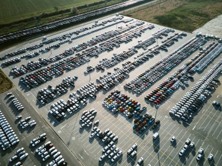 Photo for Aerial view of massive parking lot at a car manufacturing facility with newly produced vehicles parked in rows. - Royalty Free Image