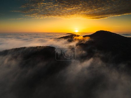 Foto de Montañas en nubes bajas al amanecer. Vista aérea del hermoso paisaje del pico de montaña en la niebla durante la mañana. - Imagen libre de derechos