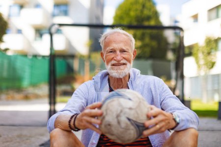 Photo for Senior man holding football, ball in his hands. Older, vital man has active lifestyle, doing sport every day. - Royalty Free Image