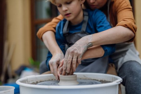Photo for Mother teaching son how to make pottery on pottery wheel. Child creative activities and art. Boy making pottery, having fun with mom. Happy family moment. - Royalty Free Image