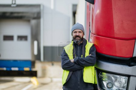 Téléchargez les photos : Chauffeur de camion debout avec les bras croisés appuyé sur son camion et regardant la caméra. - en image libre de droit