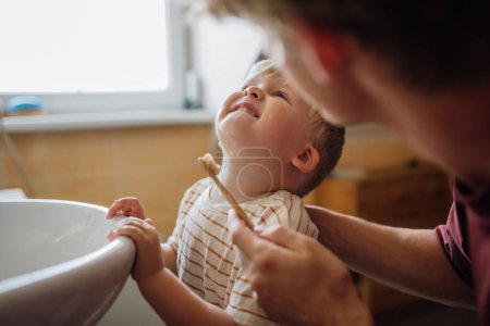 Téléchargez les photos : Père brossant les dents des petits garçons le matin. Hygiène dentaire matinale, soins pour les tout-petits. - en image libre de droit