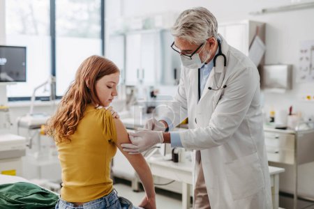 Foto de Doctor, pediatra inyectando vacuna en el brazo de una adolescente, vacunas rutinarias. Concepto de atención preventiva de salud para adolescentes. - Imagen libre de derechos