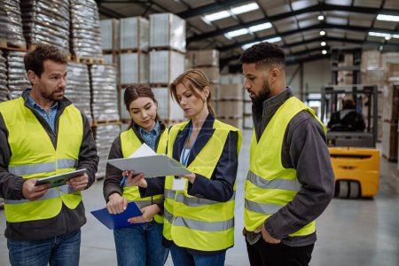 Photo for Warehouse workers reading product order, order picking. Warehouse manager checking delivery, stock in warehouse, inspecting products for shipment, talking with colleague. - Royalty Free Image