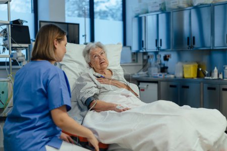 Photo for Nurse taking care of senior patient in intensive unit care, icu. Senior woman after stroke, heart attack recoverying, lying in hospital bed. - Royalty Free Image