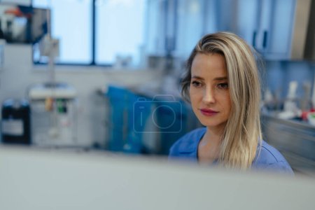 Photo for Portrait of ER doctor in hospital working in emergency room. Beautiful nurse in scrubs making call and typing on medical computer in emergency room. - Royalty Free Image