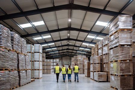 Photo for Rear view of warehouse workers in reflective vest walking in warehouse. Team of warehouse workers preparing products for shipment. - Royalty Free Image
