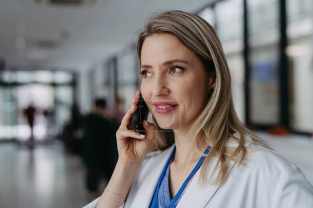 Téléchargez les photos : Portrait d'un beau médecin urgentiste au téléphone à l'hôpital. Consultations à distance avec le patient, télémédecine. - en image libre de droit