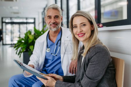 Photo for Female pharmaceutical sales representative presenting new medication, pills to doctor in medical building, looking at camera - Royalty Free Image