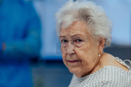 Photo for Portrait of scared senior patient on examination table in the hospital. Concept of the fear and anxiety about health problems in elderly people. - Royalty Free Image