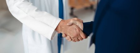 Photo for Close up of pharmaceutical sales representative shaking hands with doctor in the medical building. Doctor greeting hospital director, manager in private medical clinic. Banner with copy space. - Royalty Free Image