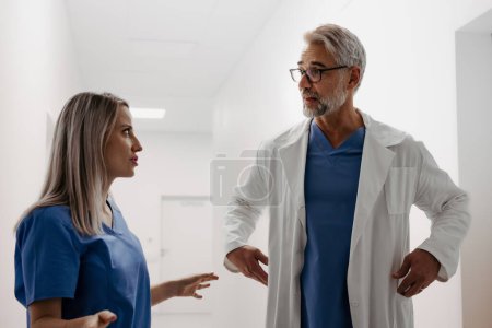 Photo for Conflict between doctors in hospital, different medical opinions or communication problems. Tense or uncomfortable work environment among healthcare workers. The nurse is angry with the doctor. - Royalty Free Image