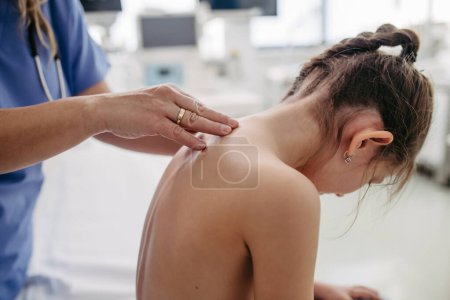 Photo for Orthopedist examines the spine, posture, and spinal deformities of little girl. Girl visiting paediatrician for annual preventive physical examination. Concept of preventive health care for children. - Royalty Free Image