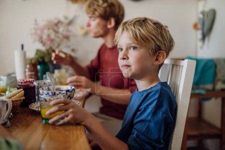 Téléchargez les photos : Jeune famille petit déjeuner ensemble dans la cuisine de la maison. Petit déjeuner ou collation Healty avant l'école et le travail. - en image libre de droit