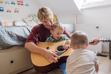 Père apprenant à jouer de la guitare. Fils s'amuser dans leur chambre avec papa, jouer de la guitare et chanter. Concept de la Journée des Pères, et amour paternel.