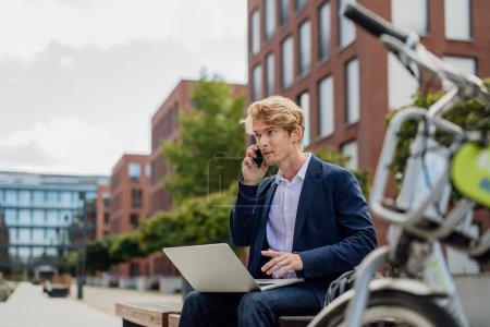 Photo for Portrait of businessman, freelancer or manager working outdoors in city park. Man with laptop on knees having video call. Concept of working remotely. - Royalty Free Image