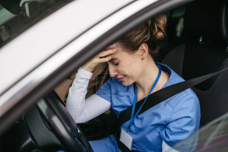 Foto de Enfermera llorando en coche, volviendo a casa después de un duro día de trabajo en el hospital. Doctor sintiéndose exhausto, frustrado, triste y enojado. Equilibrio entre vida laboral y personal sanitario. - Imagen libre de derechos
