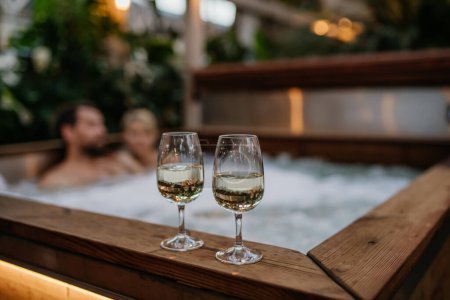 Foto de Dos copas de vino en bañera de hidromasaje, pareja relajante, disfrutando de un romántico fin de semana de bienestar en el spa. Concepto de Día de San Valentín. - Imagen libre de derechos