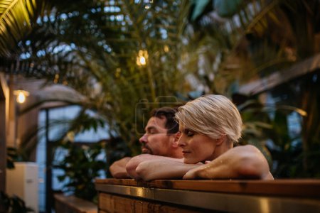 Photo for Beautiful mature couple relaxing in the hot tub, enjoying romantic wellness weekend in spa. Concept of Valentines Day. - Royalty Free Image