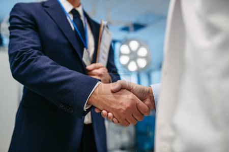 Photo for Portrait of pharmaceutical sales representative standing in doctor office, shaking hands. Hospital director, manager of private medical clinic greeting new doctor. Generous donor, giving donation to - Royalty Free Image