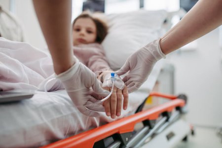 Foto de Primer plano de enfermera insertando cánula IV en vena, mano de niña. IV, terapia intravenosa para el paciente infantil. - Imagen libre de derechos