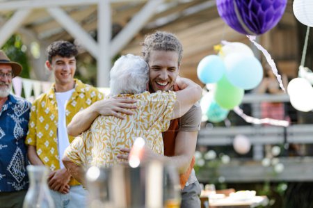 Photo for Garden birthday party for senior lady. Beautiful senior birthday woman receiving gift from grandson. - Royalty Free Image