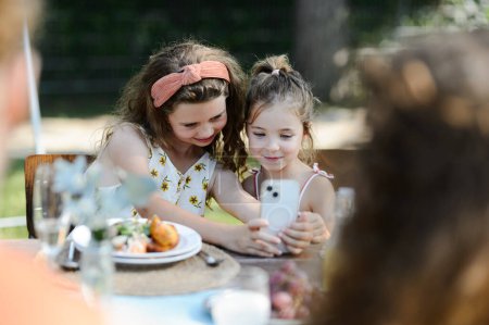 Téléchargez les photos : Cousins prenant un selfie lors d'une garden party familiale. Réunion de famille lors d'un barbecue dans le jardin. - en image libre de droit