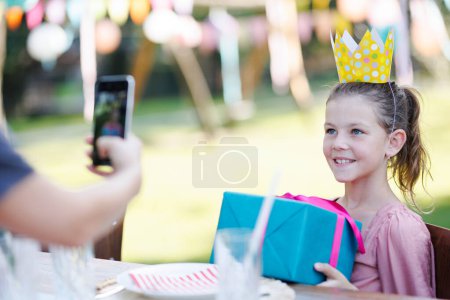 Foto de Hermosa cumpleañera sosteniendo regalo de cumpleaños posando para una foto. Fiesta de cumpleaños de jardín para niña. - Imagen libre de derechos