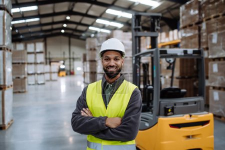 Photo for Portrait of multiracial warehouse worker standing by forklift. Warehouse worker preparing products for shipmennt, delivery, checking stock in warehouse. Banner with copy space. - Royalty Free Image