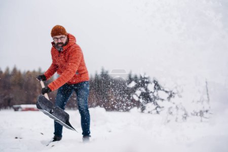 Foto de Hombre paleando nieve con pala, limpiando la entrada de su casa. Recoger y tirar nieve, palear. - Imagen libre de derechos