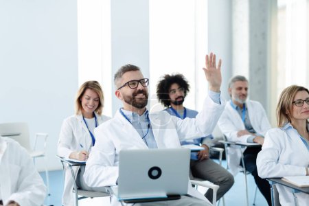 Photo for Medical team on conference, doctor raising hand asking question to speaker. Medical experts attending an education event, seminar in board room - Royalty Free Image