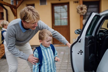 Photo for School boy getting into the car, dad helping. Father taking son to school before going to work. - Royalty Free Image