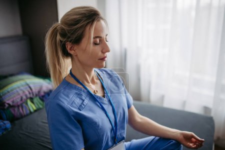 Photo for Close up, nurse or doctor enjoying free time at home after work, meditating in bedroom. Work-life balance for a healthcare worker. - Royalty Free Image