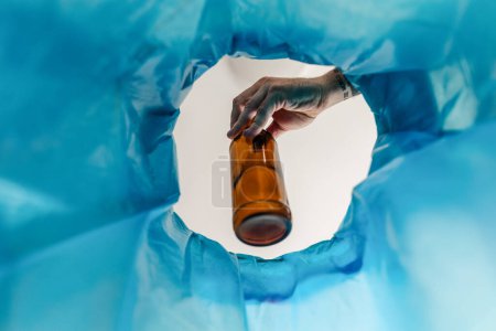 Photo for Man throwing glass bottle into recycling bin. Throwing empty alcohol bottle, New Years resolutions, drink less alcohol healthy lifestyle without alcoholic drinks. - Royalty Free Image