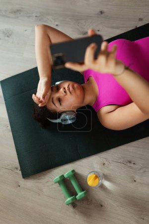 Photo for Woman resting after home workout, New Years resolutions, healthy lifestyle, losing weight and selfcare. Concept of morning or evening workout routine. - Royalty Free Image
