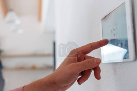Foto de Primer plano del termostato inteligente, ajustando o bajando las temperaturas de calefacción en el hogar. Concepto de tecnología sostenible, eficiente e inteligente en calefacción doméstica y termostatos. - Imagen libre de derechos