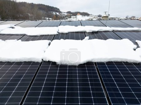 Téléchargez les photos : Panneaux solaires sur le toit avec de la neige dessus. L'énergie solaire en hiver. - en image libre de droit