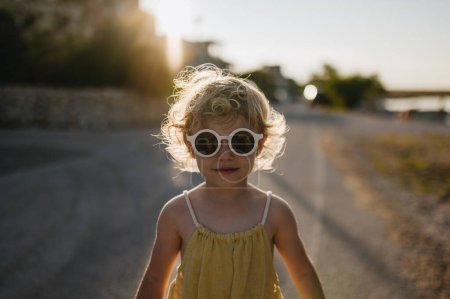 Téléchargez les photos : Portrait de fille blonde en tenue d'été et lunettes de soleil en promenade pendant les vacances d'été, concept de vacances à la plage. - en image libre de droit