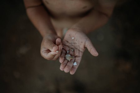 Foto de Primer plano de conchas marinas en la palma de los niños con dedos de ciruela. Sirviendo conchas en la arena. Concepto de vacaciones de verano por mar. - Imagen libre de derechos