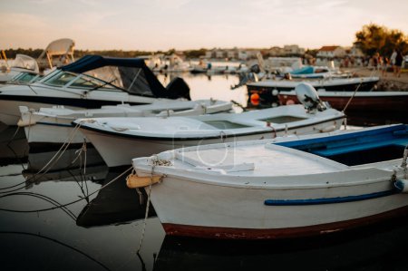 Téléchargez les photos : Un petit bateau sur l'eau calme, amarré dans le port, quai pendant le coucher du soleil. - en image libre de droit