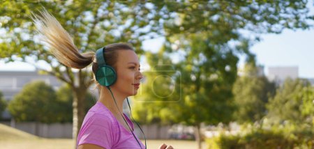 Junge Frau läuft ins Freie und hört Musik. Sport nach der Arbeit fördert die psychische Gesundheit, die körperliche Gesundheit, den Stressabbau und die Stimmung. Banner mit Kopierraum.