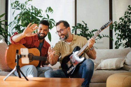 Photo for Best friends, musician jamming together, making video on social media. Playing music on acoustic and electric guitar together at home for fans. Concept of male friendship, bromance. - Royalty Free Image